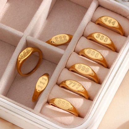 Set of gold angel number rings with engraved numbers in a jewelry box